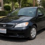 Czarny sedan Honda zaparkowany przy krawężniku na spokojnej, zadrzewionej ulicy